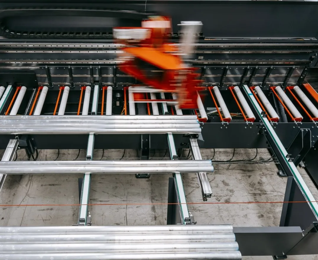 Detailansicht der Briganto CrossCut Profil- und Ablängsäge: Aluminiumprofile auf dem Rollenbahnsystem während des automatisierten Bearbeitungsprozesses.