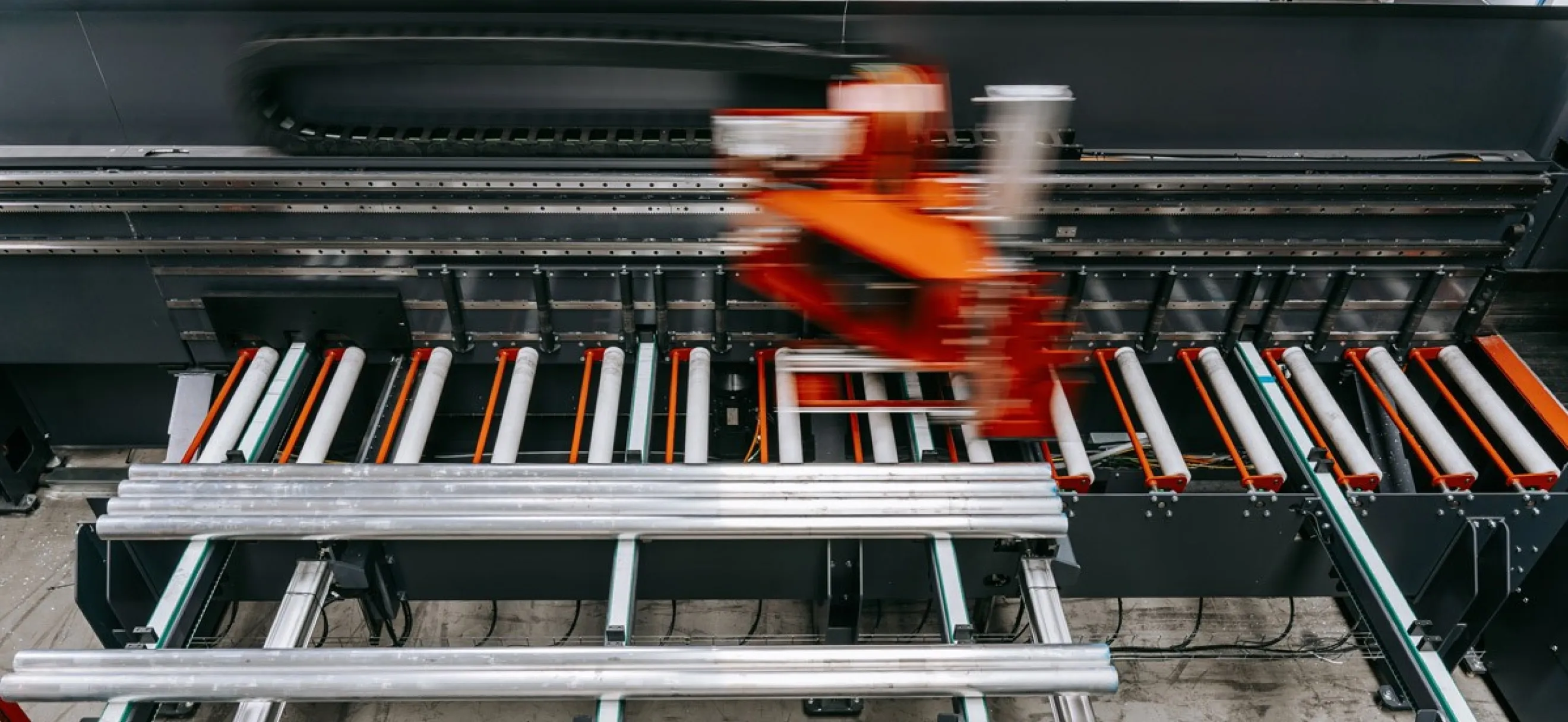 Detailansicht der Briganto CrossCut Profil- und Ablängsäge: Aluminiumprofile auf dem Rollenbahnsystem während des automatisierten Bearbeitungsprozesses.
