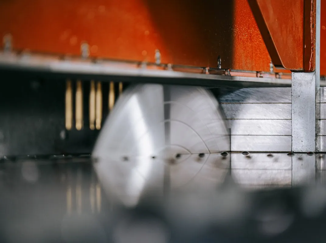 Detailaufnahme eines rotierenden Sägeblatts der Alu Preciser Plattensäge von Briganto beim präzisen Zuschnitt von Aluminium.